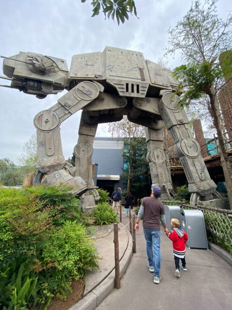 father and son walk through Star Tours Entrance featuring AT AT Walker