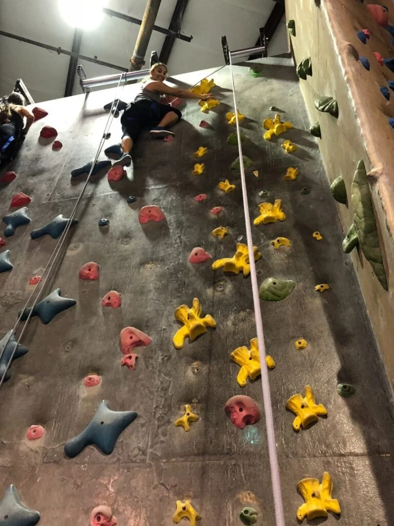 woman at the top of rock climbing wall at Aiguille Rock Climbing Center