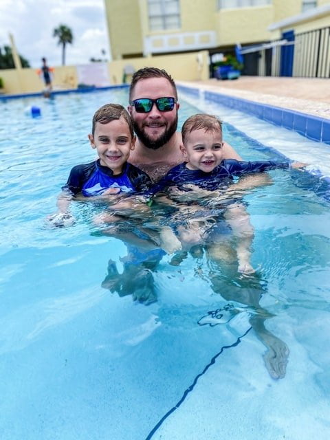 a dad in the pool with his two sons
