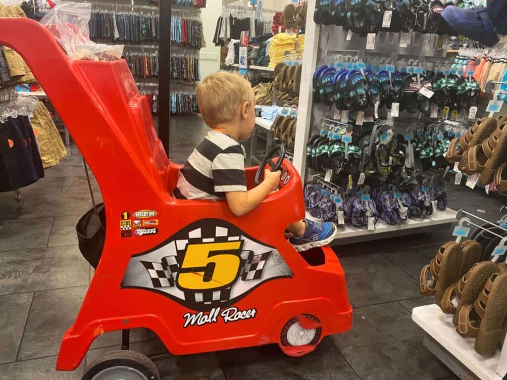 young boy sitting in Race Car Stroller at Altamonte Mall