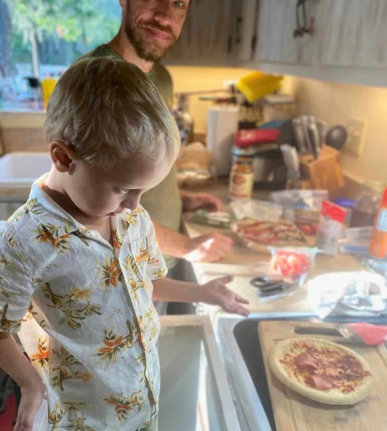 a father and son prepare pizza together in their home kitchen
