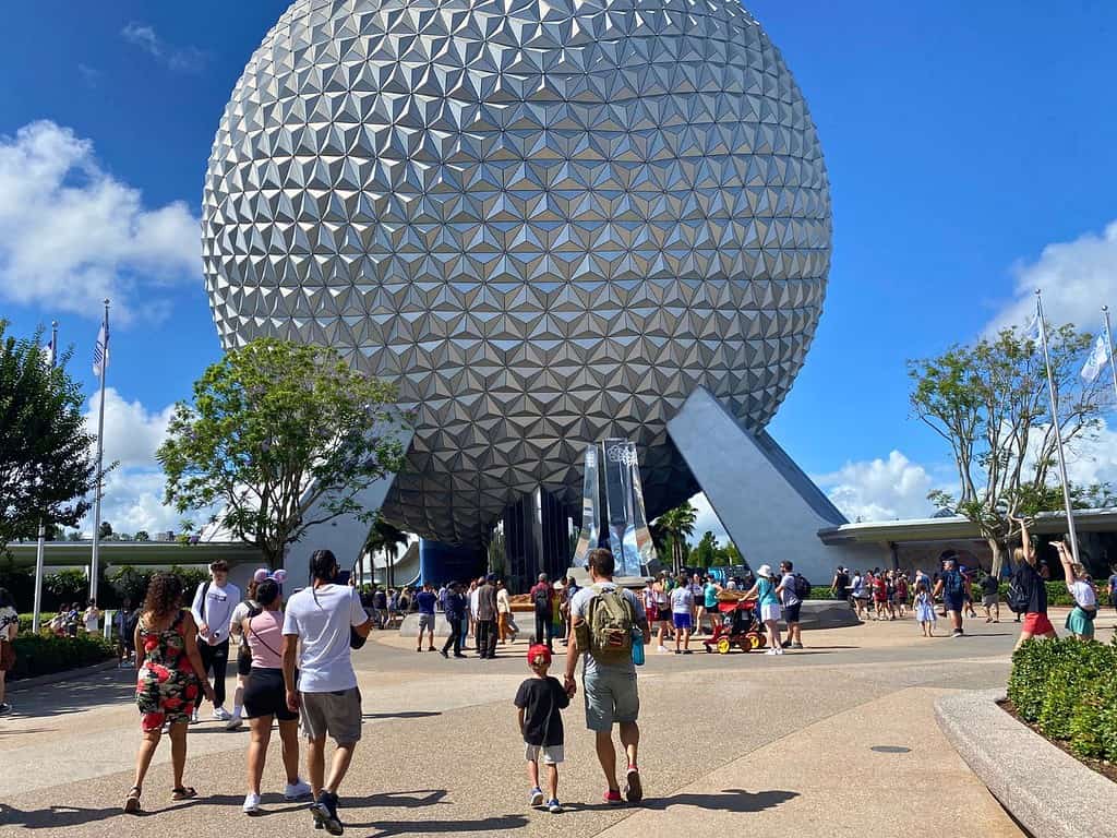 Visiting EPCOT in the Summer a husband and young son walk towards Spaceship Earth