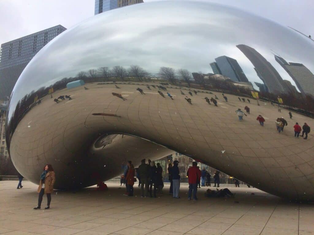 a woman in jacket and scarf poses in front of Chicago Bean structure