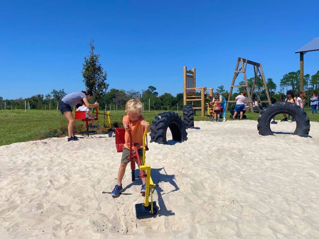 young boy uses a digger in a sand play area at Amber Brooke Farms near Orlando
