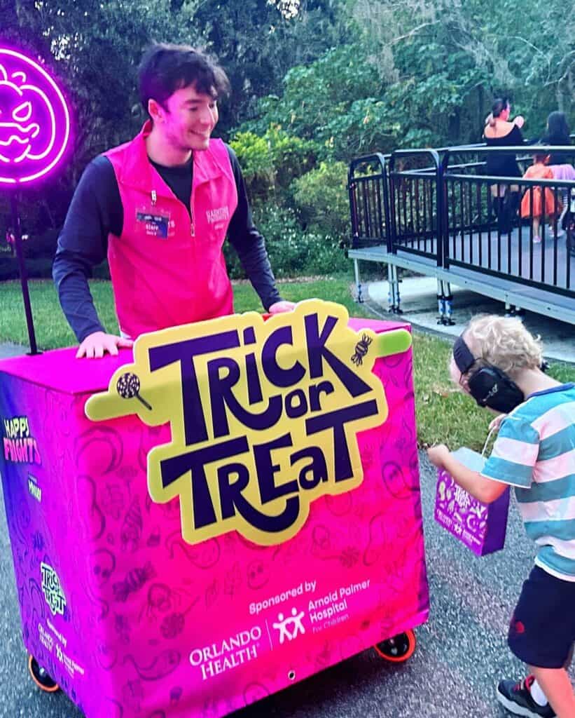 a young boy at a trick or treat station at happy frights leu gardens
