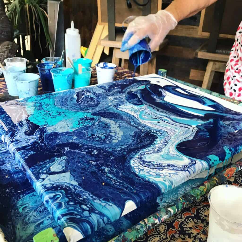 blue paint is poured on a canvas during Fluid Art Class in Orlando 