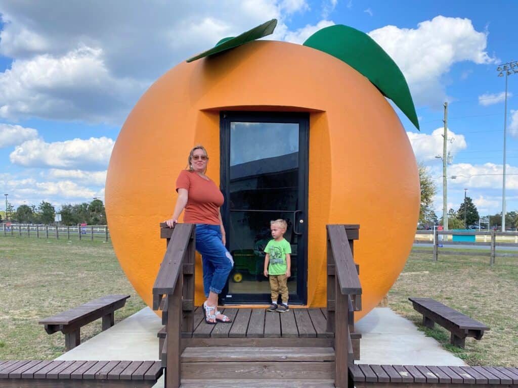 Image and woman and male child standing in front of the Sunsational Farms Giant Orange