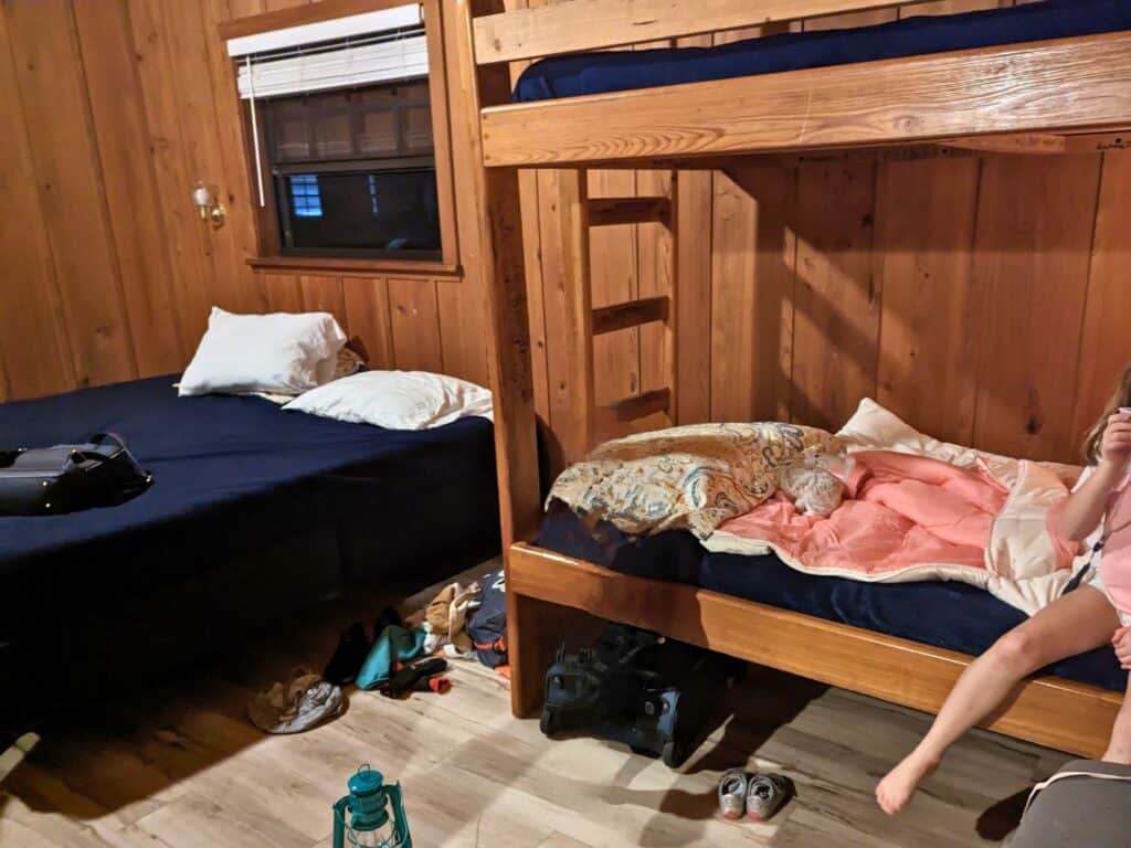 Image of queen sized bed and twin bunk beds in a cabin at Otter Springs