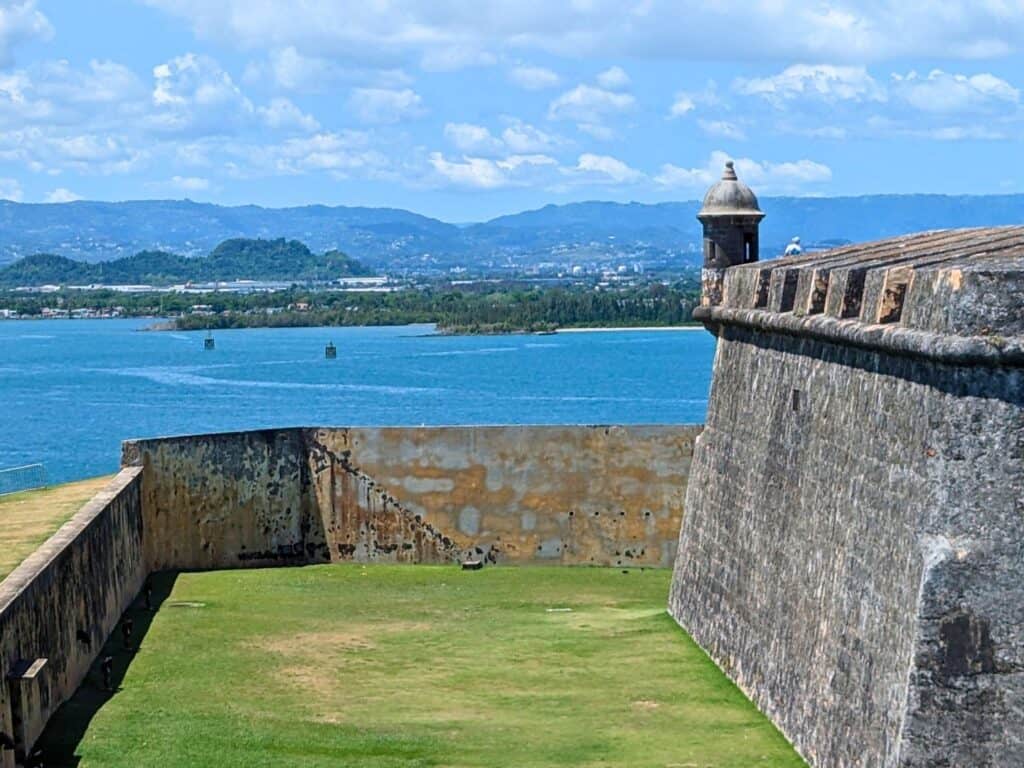 Image of a historic fort on the water in Puerto Rico with mountains in the background
