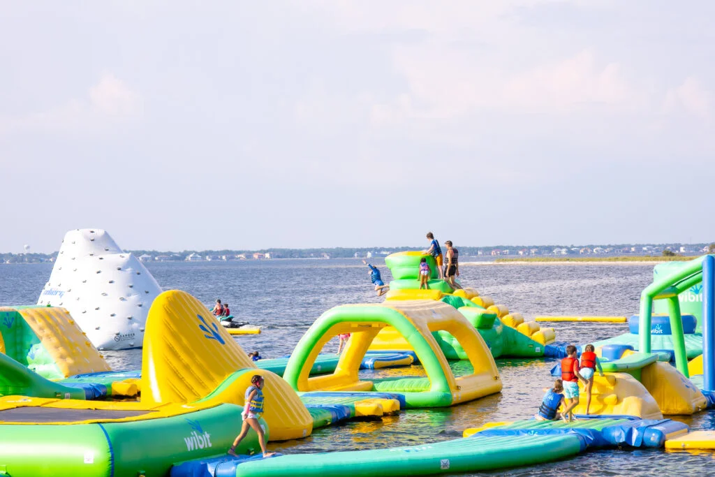 Kids on inflatable water park in ocean Portofino Island Resort, Pensacola Beach FL