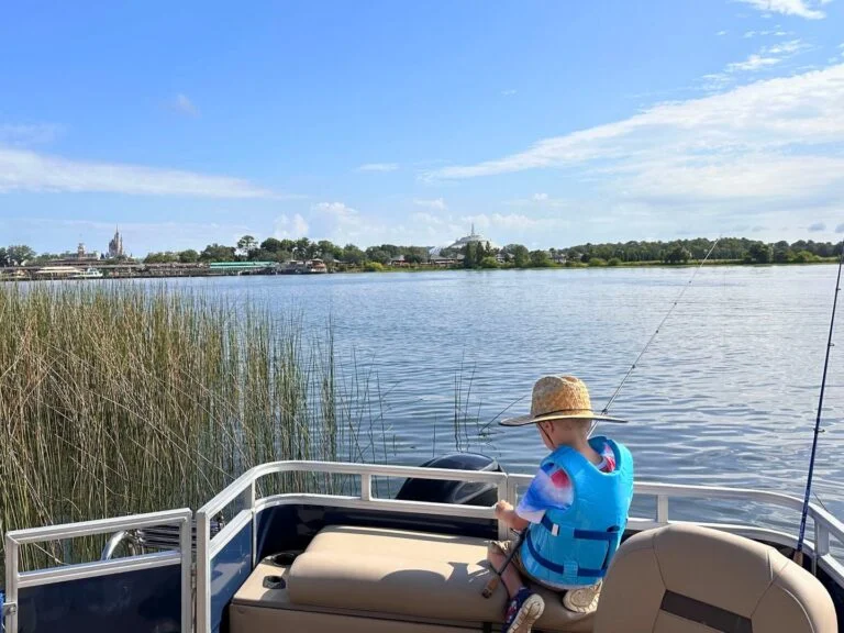 Young boy with fishing pole during fishing at Walt Disney World in front of Magic Kingdom
