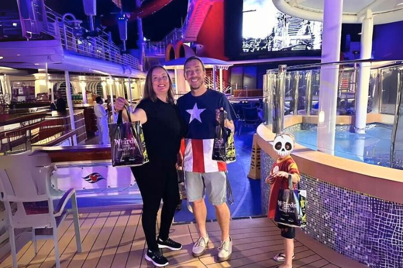 Family of 3 poses with Disney Cruise Line trick or treat bags - image from Dani Meyering