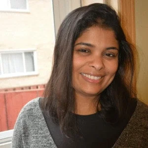 Anu Varma Panchal, a smiling woman with medium-length dark hair, wearing a gray sweater