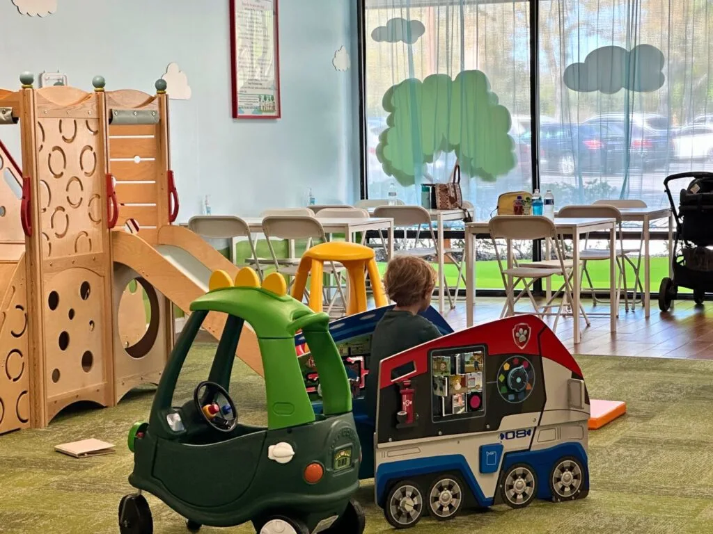 Wooden play structure indoors and play vehicles at The Play Fort Deltona facing outward - image by Dani Meyering