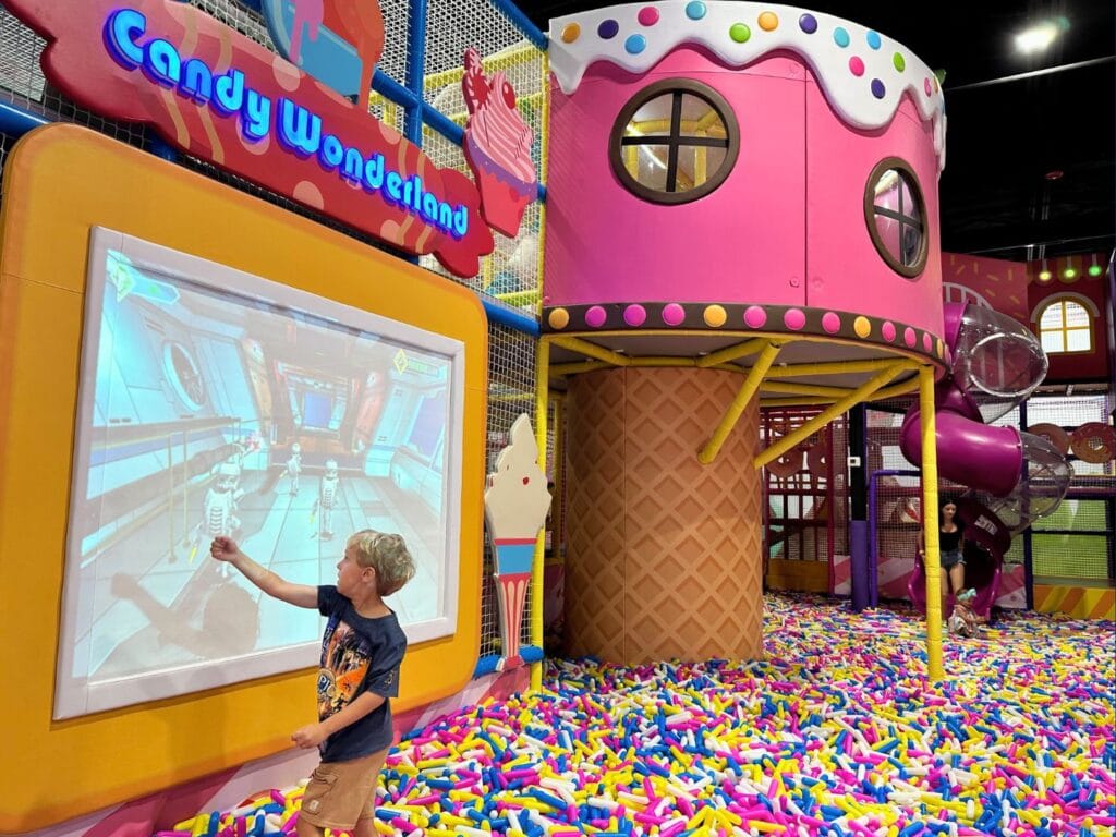Candy Wonderland in Palm Bay young boy plays screen game with while inside a sprinkles style ball pit - image by Dani Meyering