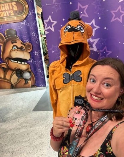 Editor Dani Meyering wearing the Deathly Afraid Necklace in front of a Five Nights at Freddy's Display HHN - image by Dani Meyering