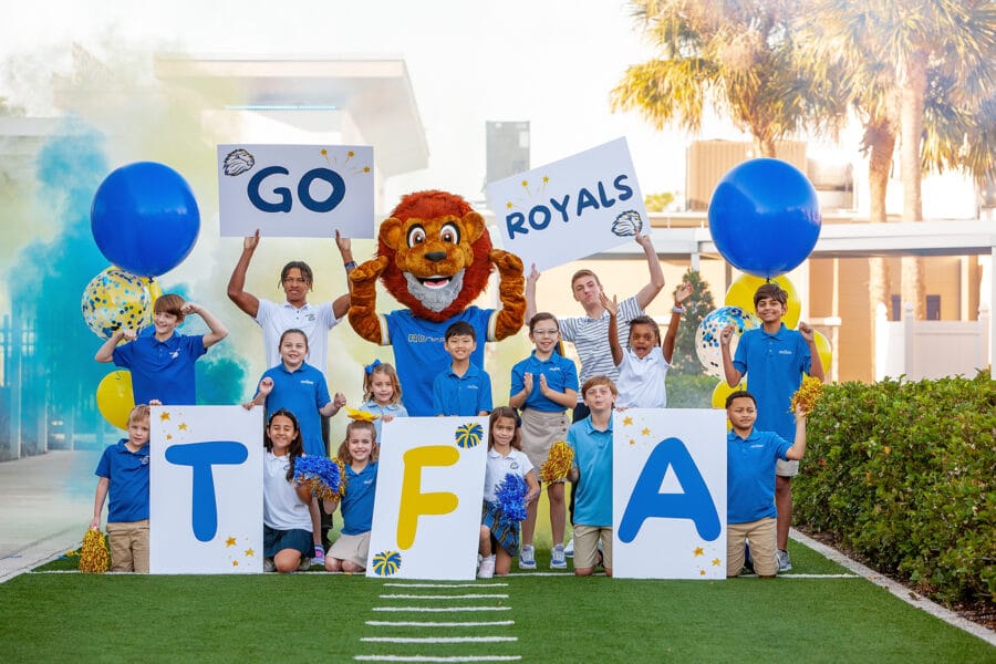 The First Academy students with Mascot holding signs