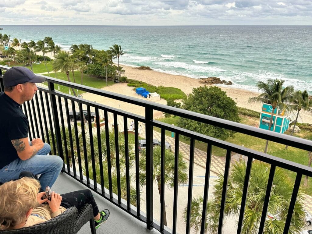 Father and son on balcony of King Suite at Embassy Suites Deerfield Beach - image by Dani Meyering