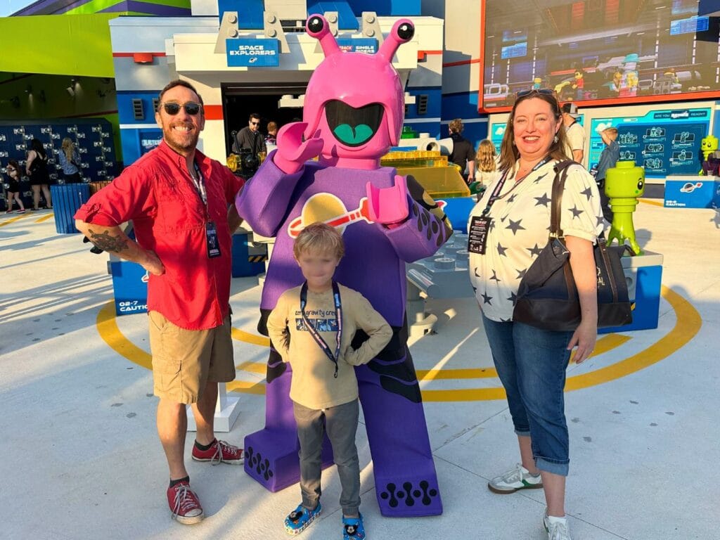 Family of three pose with character at Galacticoaster entrance - image by Dani Meyering