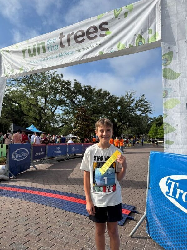 A boy shows off his participation ribbon for a family 5k from Track Shack in Orlando