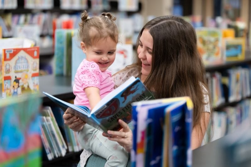 A mother and daughter looking at a book in the Orlando county public library