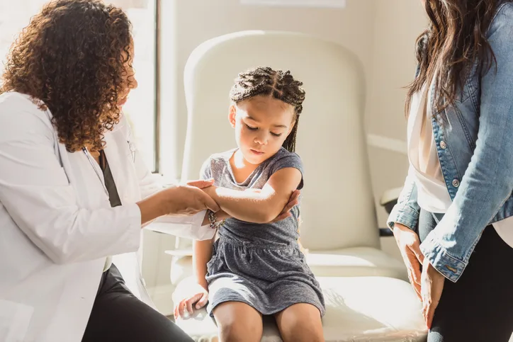 Nemours Unrecognizable pediatrician gently holds preschool child's injured arm. Doctor and patient eczema