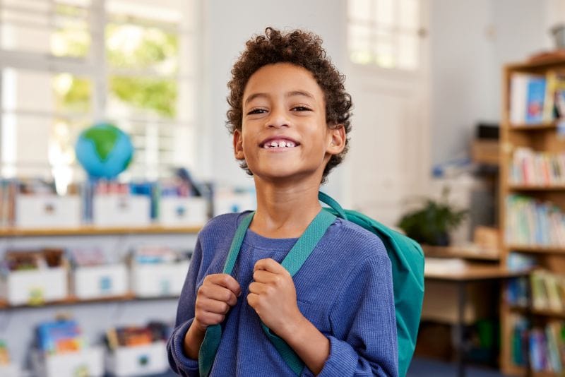 Proud elementary education student wearing a backpack feeling good about the Orlando-area school he attends
