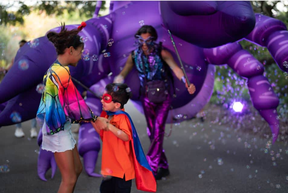 a performer using a purple inflatable crab puppet entertains kids in halloween costumes at Happy Frights event orlando